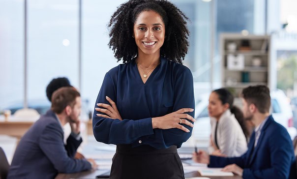 Advogada sorridente em reunião de negócios com equipe diversificada, ambiente corporativo profissional e moderno.