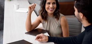 Advogada sorridente atendendo cliente em escritório de advocacia.