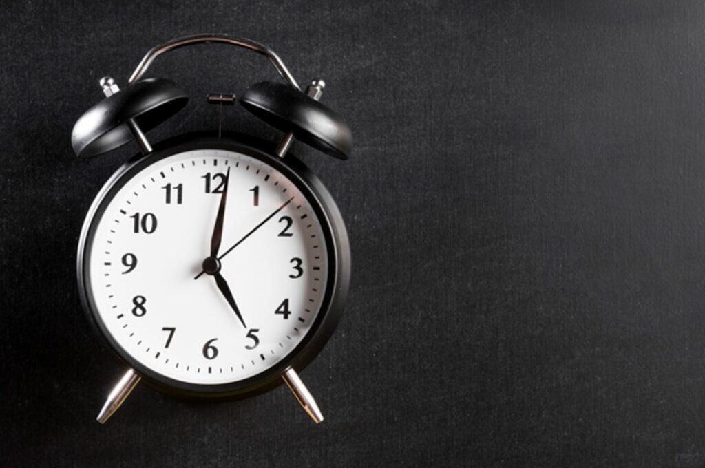 Despertador preto clássico, representando pontualidade no ambiente de trabalho.