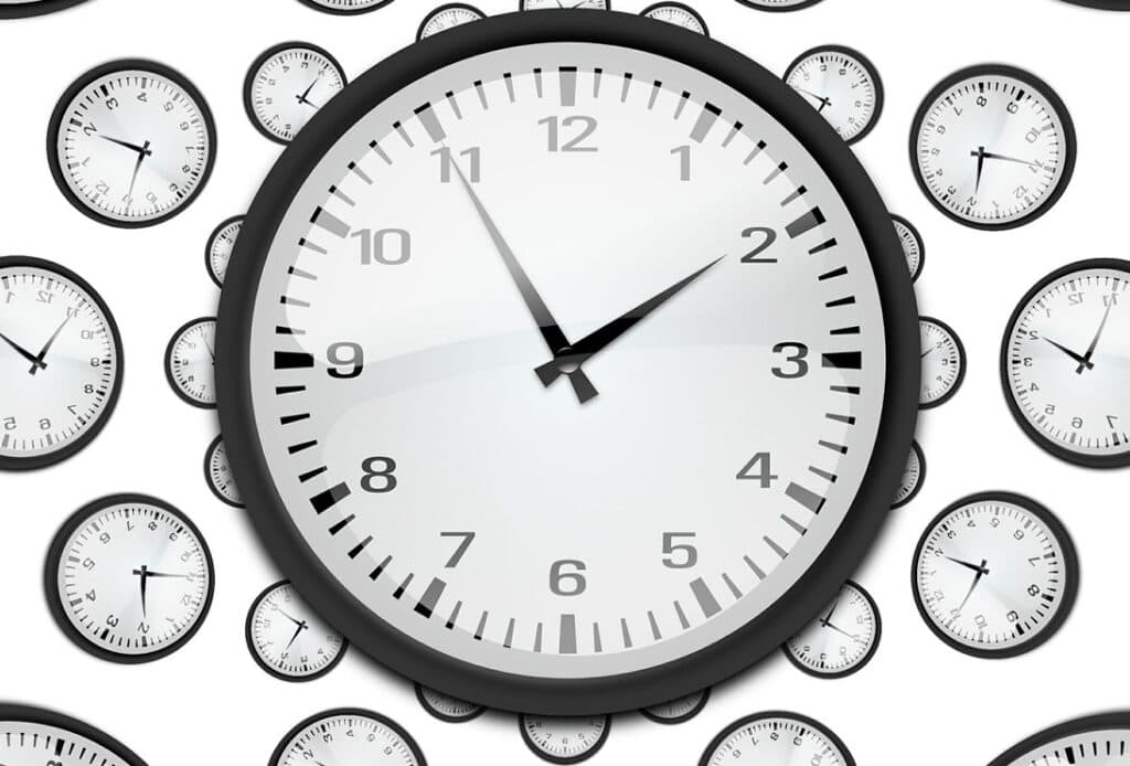 Relógios de parede com números e ponteiros, foco em gestão de tempo e produtividade.