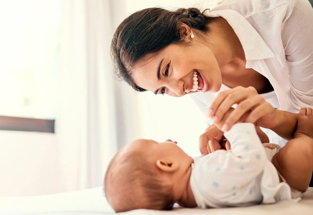 Cuidadora brincando com bebê sorridente, cuidado infantil e alegria, vendendo serviços de cuidado infantil.