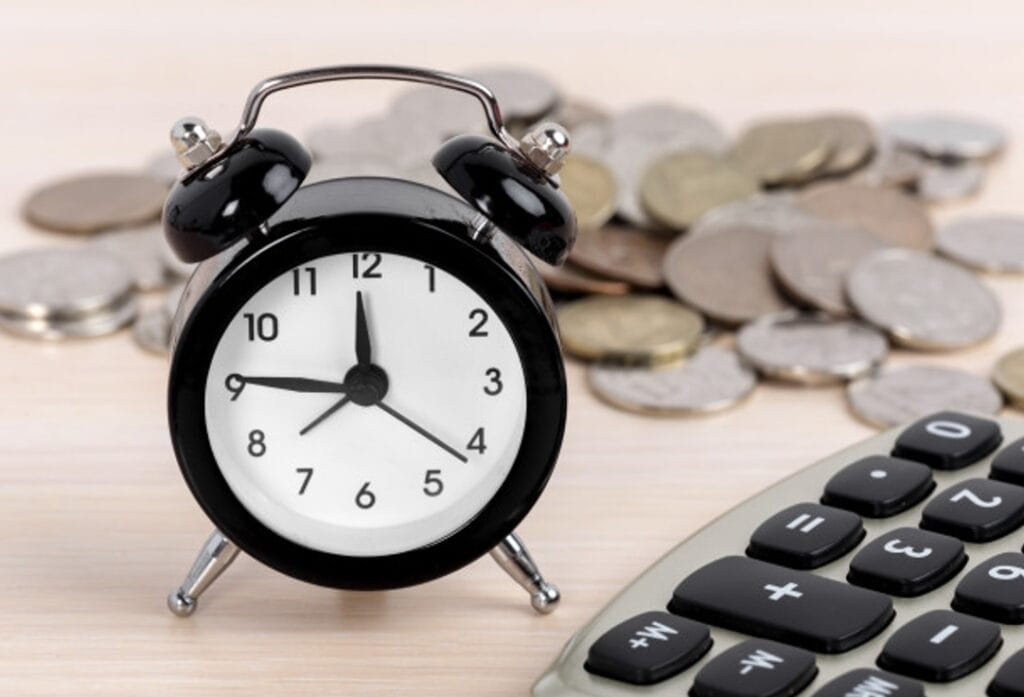 Relógio de alarmes com moedas e calculadora para finanças e economia.