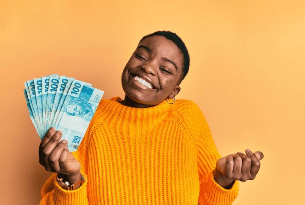 100 reais em dinheiro, mulher sorridente com orgulho, conceito de ganhos financeiros.