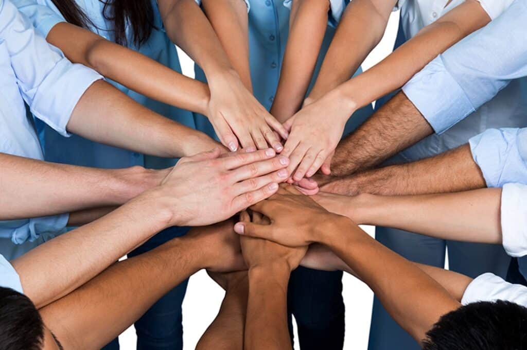 Unidos em equipe de trabalho com mãos empilhadas mostrando colaboração e parceria.