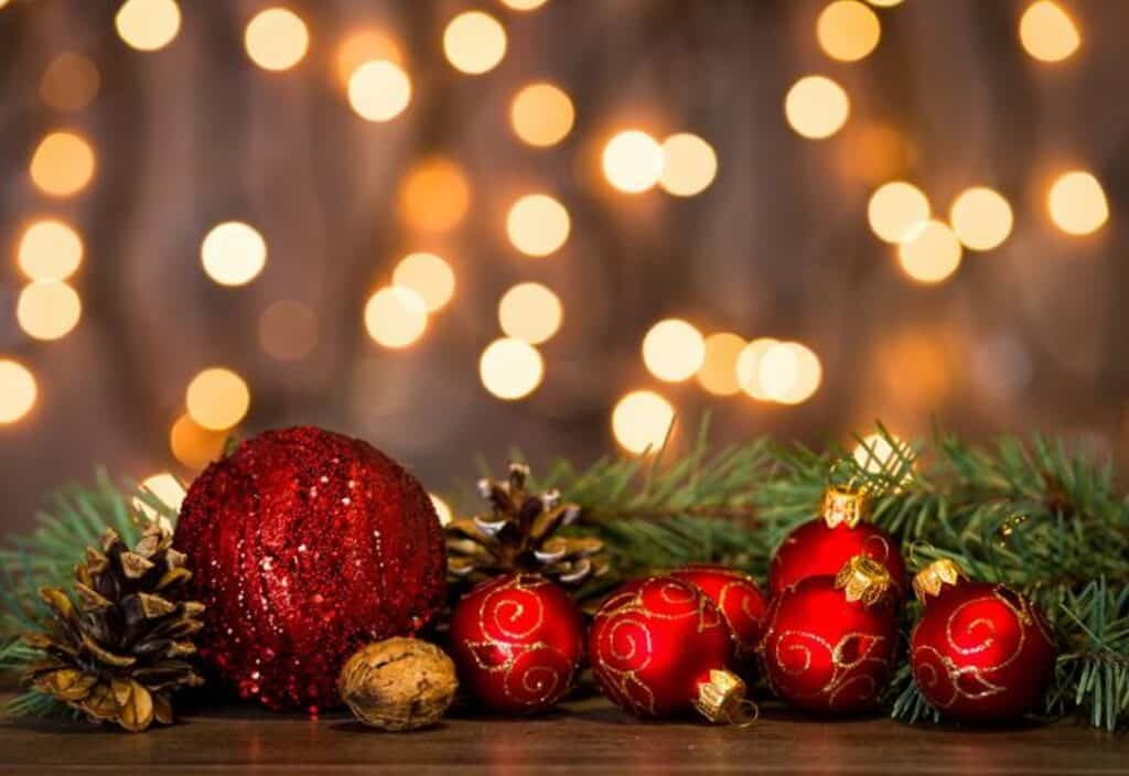 Bola de Natal vermelha, ramos de pinheiro e decoração festiva com luzes brilhosas.