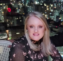 Profissional sorridente em ambiente urbano com vista noturna, representando confiança e excelência no serviço legal.