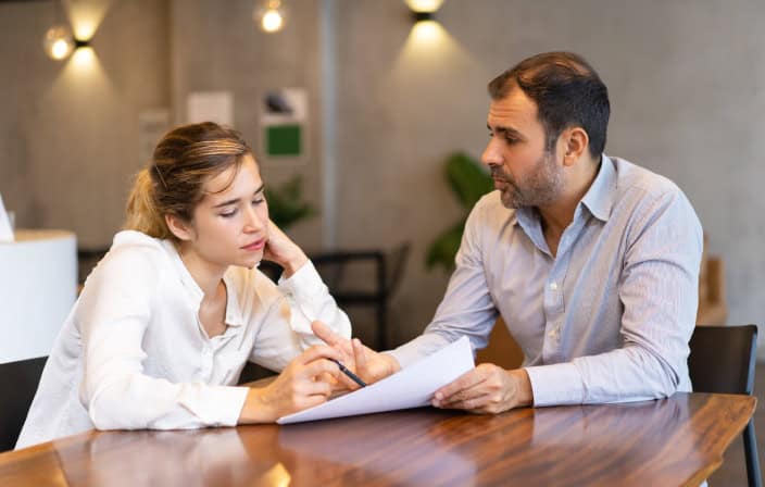 Duas pessoas conversam e analisam um documento.